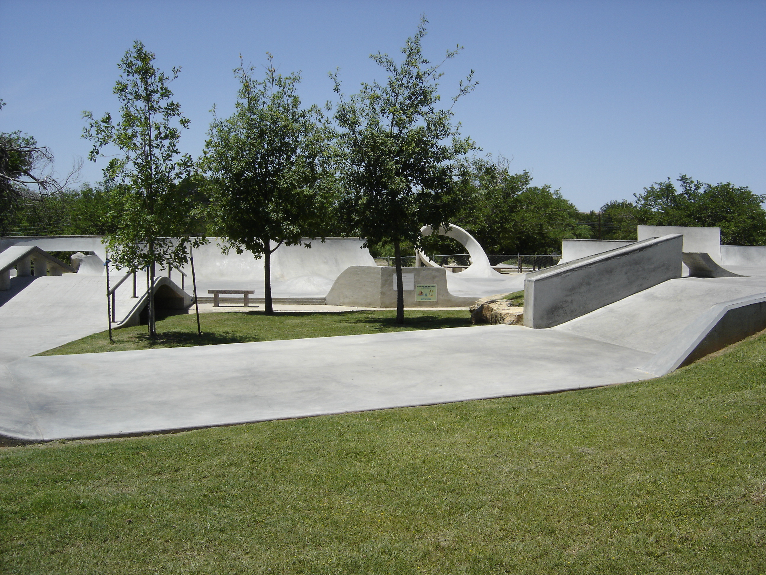 Grassy area with trees in the center of the skate park.